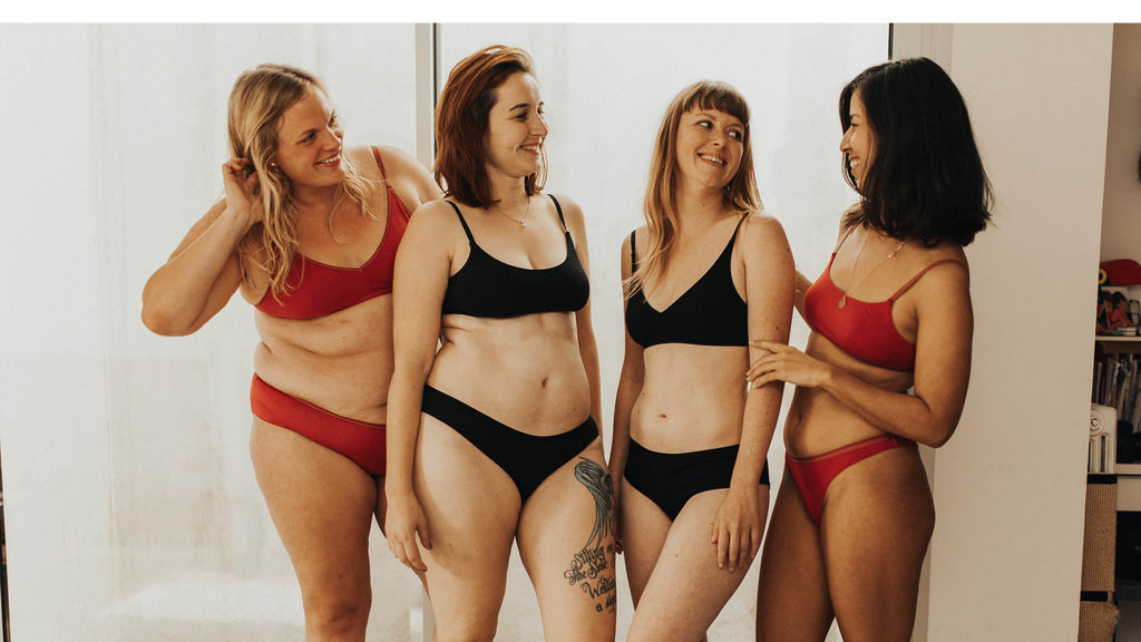 4 femmes debout devant une porte vitrée, habillée en lingerie. Elles portent soutien-gorge sans armature ou brassière en coton biologique, coloris noir ou rouge 