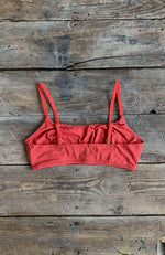 Dos d'une brassière rouge terracotta posée sur une table en bois
