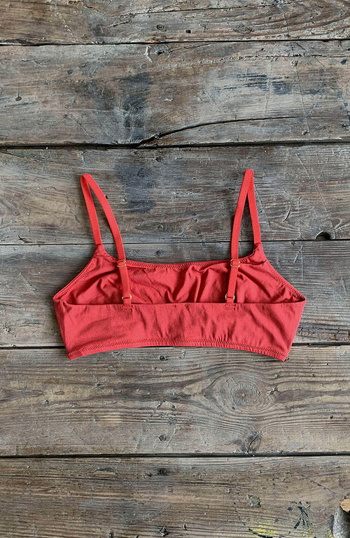 Dos d'une brassière rouge terracotta posée sur une table en bois