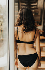 Femme de dos devant des escaliers, portant des sous-vêtements en coton bio noir