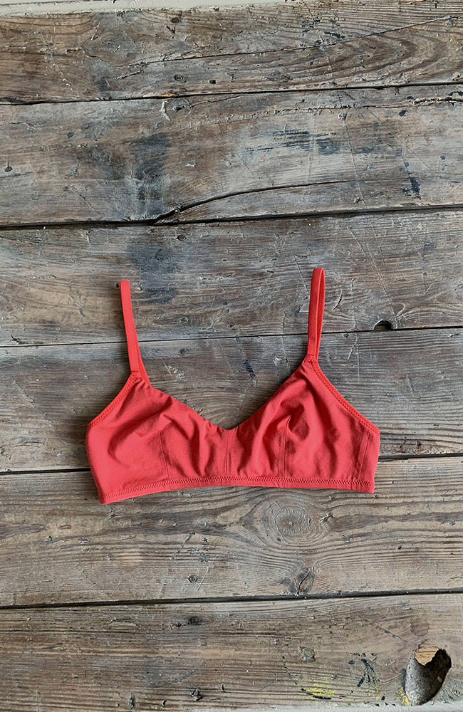 Soutien-gorge sans armature en coton rouge terracotta posé sur une table en bois