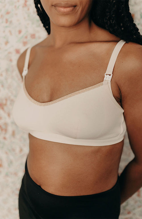 Femme debout portant un soutien-gorge de grossesse de couleur crème, détails dorés