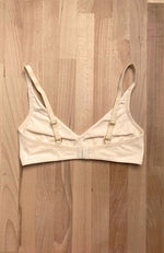 Soutien-gorge posé à plat, de dos, sans armature et sans rembourrage, de couleur crème, bretelles réglables